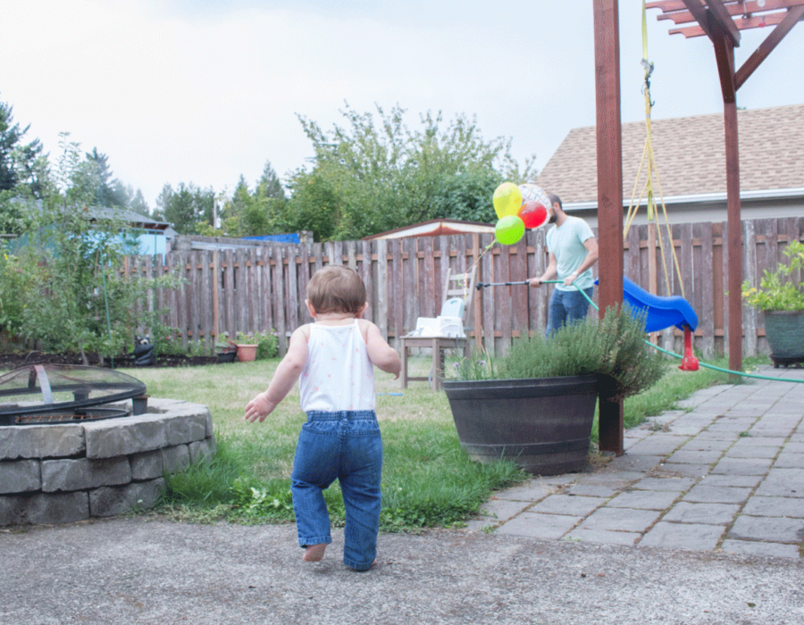 first-birthday-baby-running-towards-balloons-outside-firepit-lawn